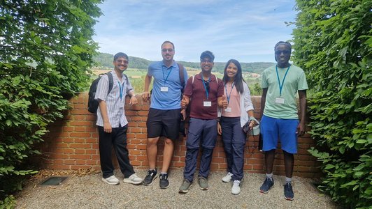 Scholars standing outside in front of a wall and smiling