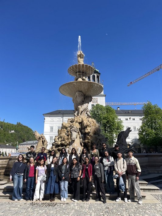 Group photo of scholarship holder standing in front of a statue in Salzburg