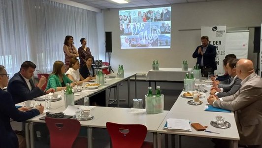 Schulleiter begrüßt die Besuchergruppe in einem Seminarraum.