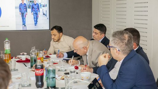 Menschen sitzen am Tisch und machen Notizen