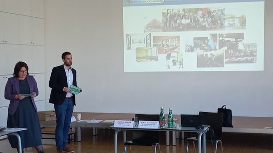 Eine Frau und ein Mann machen einen Vortrag, ein Bild ist auf den Wand projiziert.