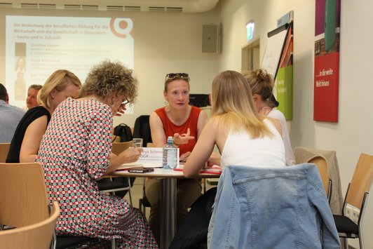 Menschen sitzen beim Tisch.