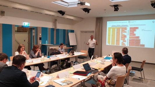 Menschen sitzen im Saal und hören eine Präsentation übers das Bildungssystem in Österreich zu.